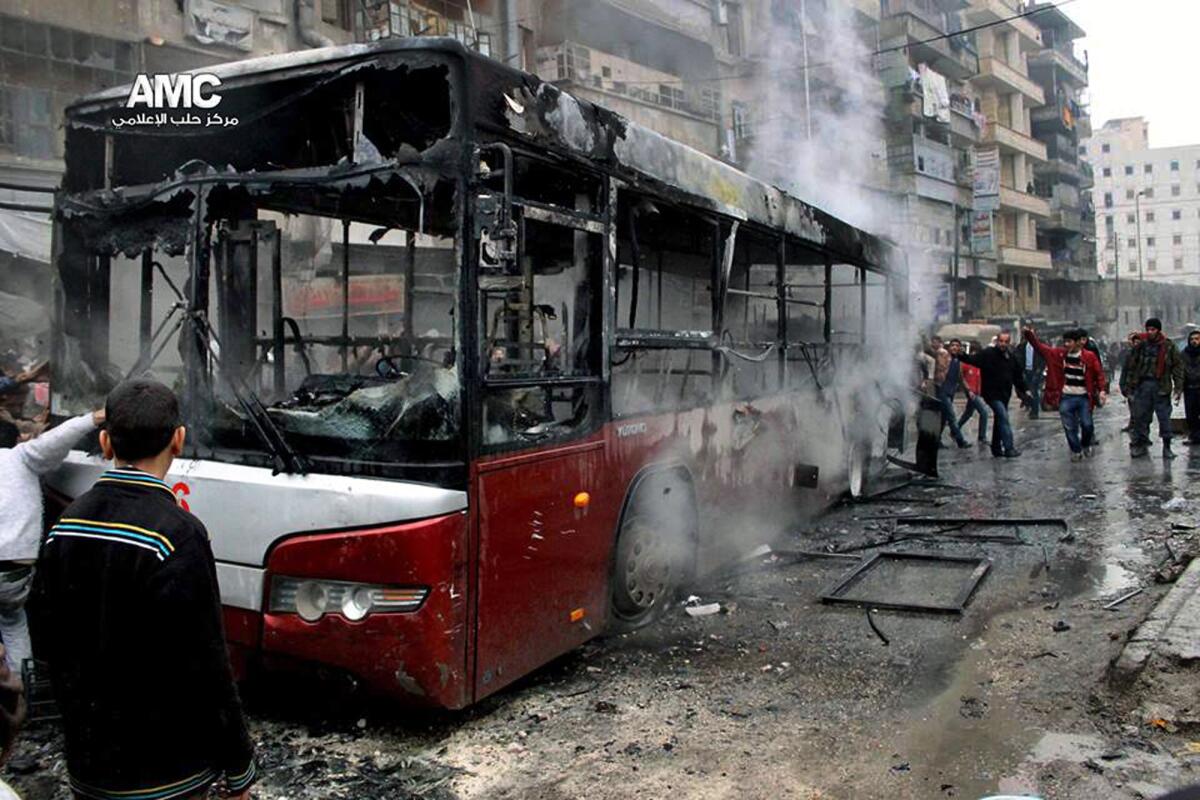 This image provided by Aleppo Media Center, which has been authenticated based on its contents and other Associated Press reporting, shows Syrians inspecting a burnt bus after a missile fired by government aircraft hit the vehicle Tuesday in Aleppo. On Wednesday, a missile reportedly fired by government forces hit a residential building in the city, killing at least 20 people.