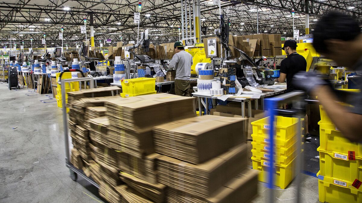 Workers pack items last month at an Amazon facility in San Bernardino.