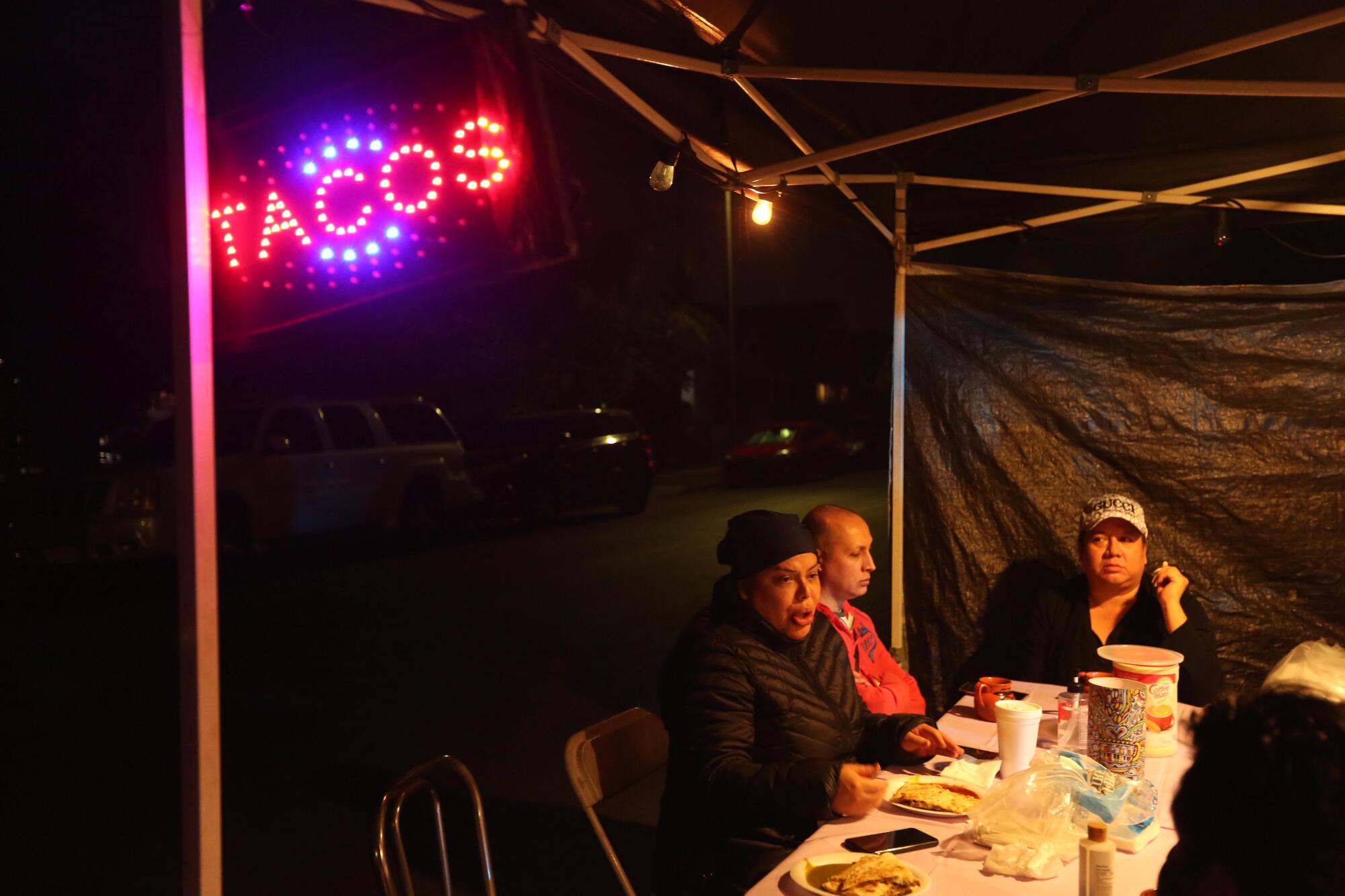Vanessa Antonely, left, Chantal Fernandez and Lluvia Guzman hang out at Maria Rosa Garcia's taco stand.