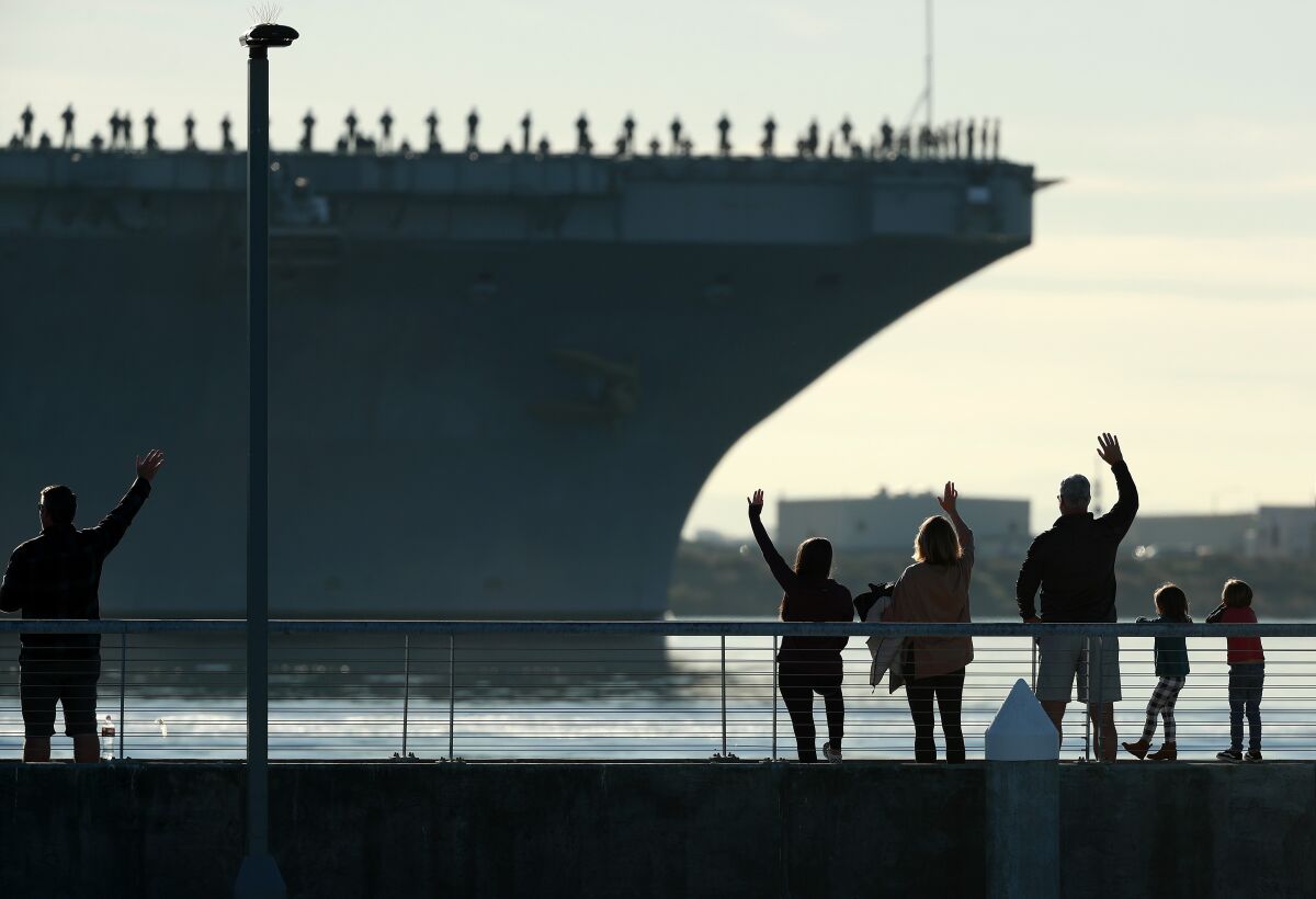 Families wave to the aircraft carrier USS Abraham Lincoln (CVN-72) as it leaves San Diego.