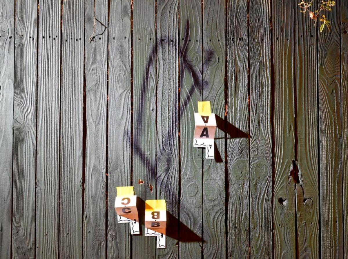 A wooden fence with graffiti and evidence markers