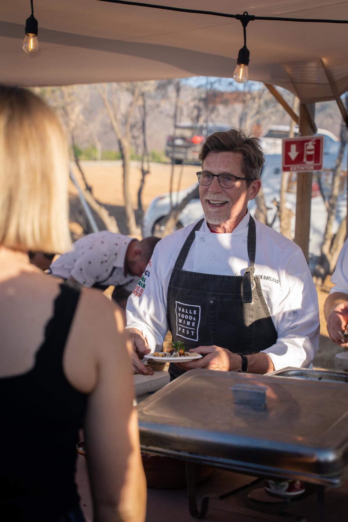 Chef Rick Bayless serving food to diners at the 2019 Valle Food & Wine Festival in Baja's Valle de Guadalupe.