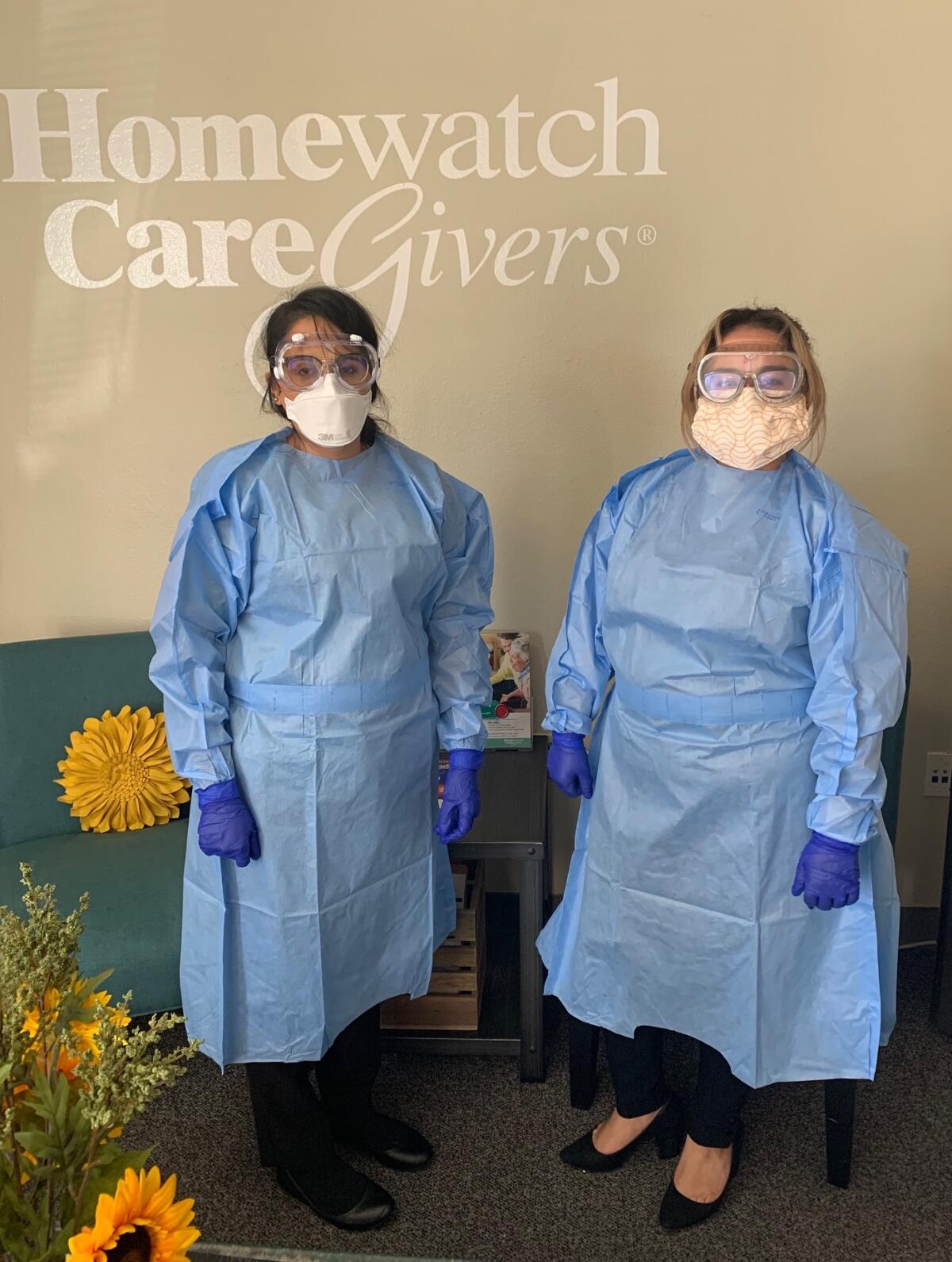 Two Homewatch Caregivers staff members stand ready in their personal protective equipment.
