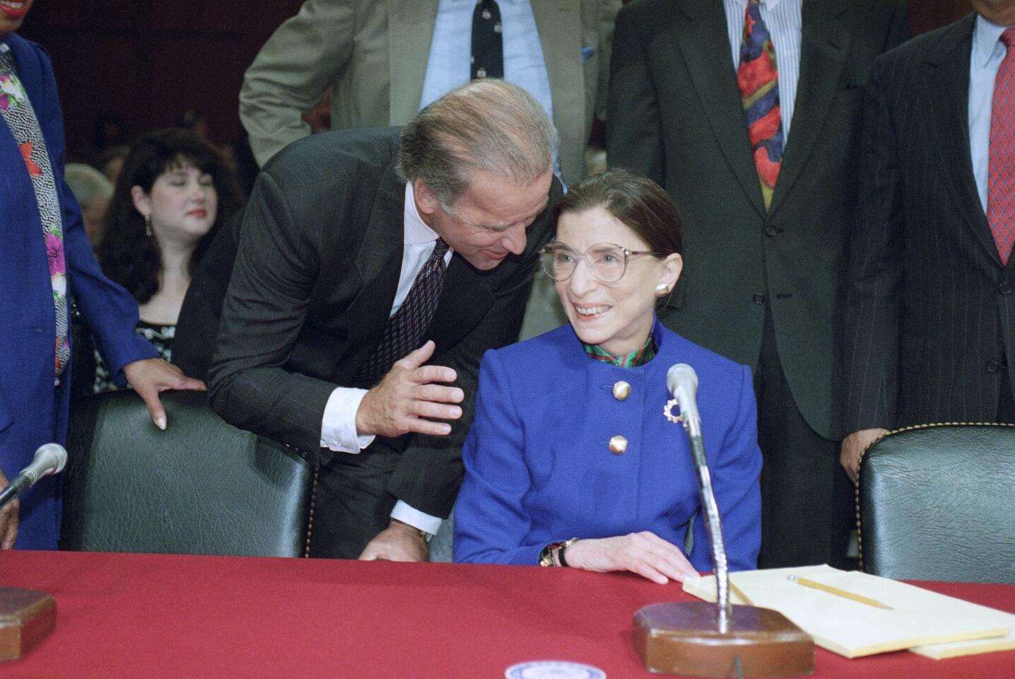 Joe Biden leans down to talk to Ruth Bader Ginsburg, seated in front of a microphone before her Senate confirmation hearing