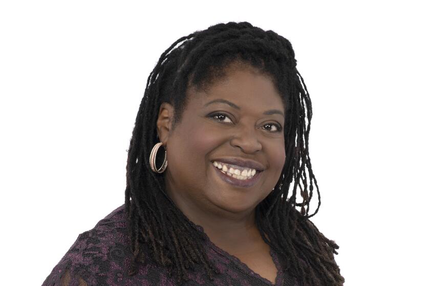 A woman with braids and hoops wearing a purple lace dress smiling at the camera