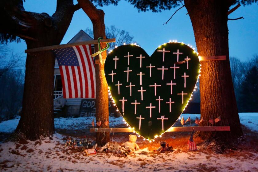 FILE - In this Dec. 14, 2013, file photo, a makeshift memorial with crosses for the victims of the Sandy Hook Elementary School shooting massacre stands outside a home on the first anniversary of the tragedy in Newtown, Conn. Five years later, residents are dealing with what it means to be from a place whose name has become synonymous with tragedy. Mary Ann Jacob, who was a school library clerk the day of the shooting and who became the chair of the town's legislative council in 2013, said "Some days it sits quietly by your side, and you acknowledge it and know it's there and move on with your day. Other days it's a really hard, difficult burden to bear." (AP Photo/Robert F. Bukaty, File)