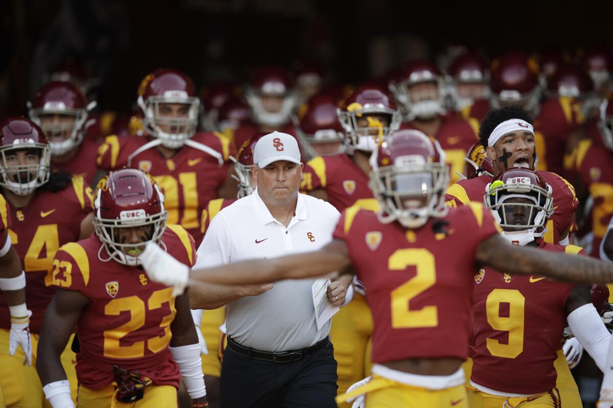 USC coach Clay Helton runs onto the field with his team before a game against Utah.