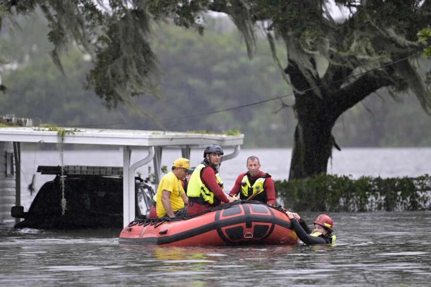 First responders with Orange County Fire Rescue use an inflatable boat to rescue a resident from a home in the aftermath of Hurricane Ian, Thursday, Sept. 29, 2022, in Orlando, Fla. Climate change added at least 10% more rain to Hurricane Ian, a study prepared immediately after the storm shows. (AP Photo/Phelan M. Ebenhack)