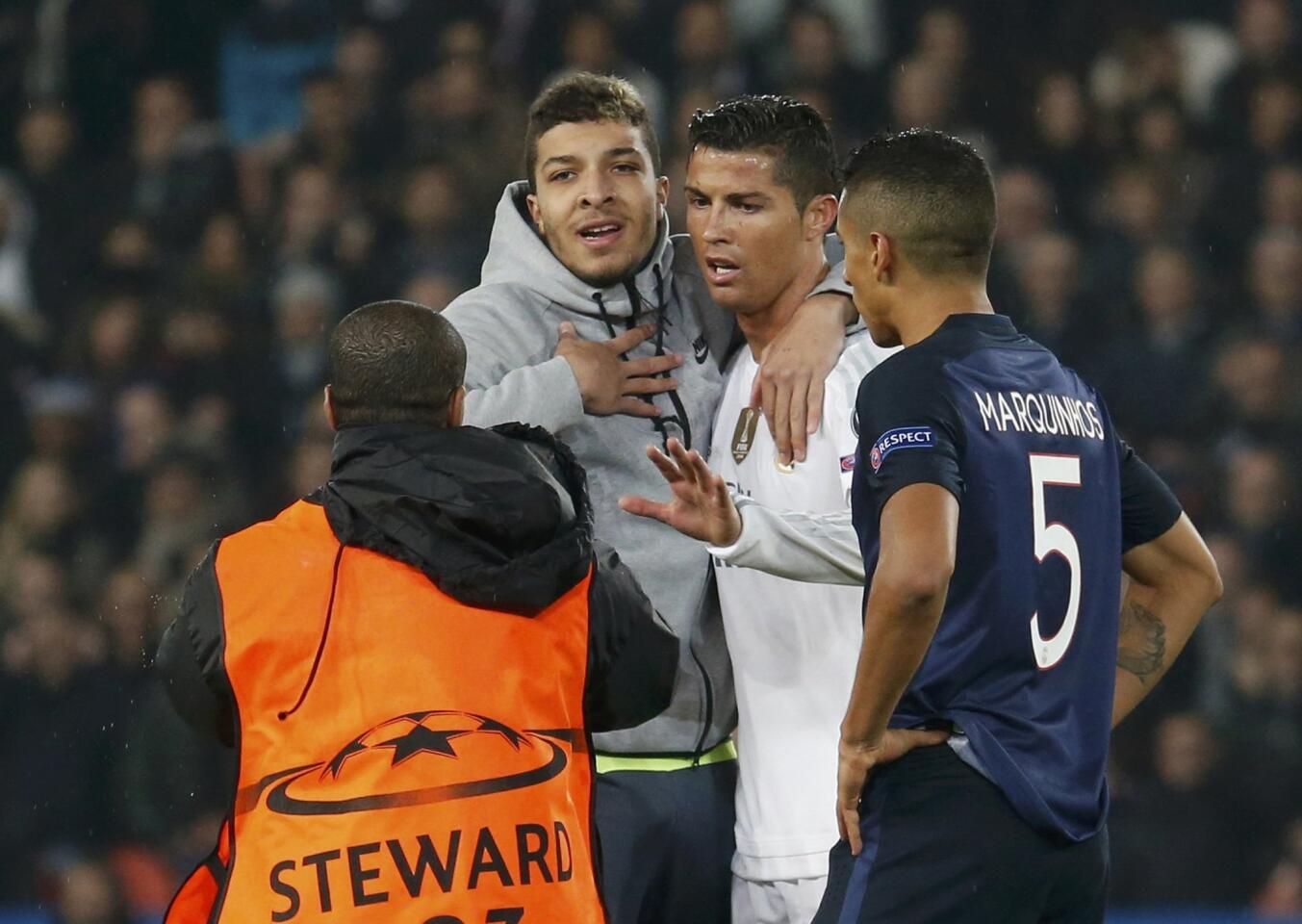 Real Madrid's Cristiano Ronaldo gestures as a security steward arrives to remove a fan who ran onto the pitch during their Champions League Group A soccer match against Paris Saint Germain at the Parc des Princes stadium in Paris