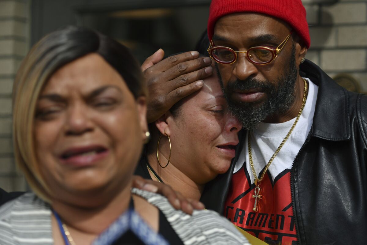 Antoinette Walker cries on the shoulder of Frank Turner as Penelope Scott speaks to the media during an interview at the corner of 10th and K street in Sacramento, Calif., on Monday, April 4, 2022. Walker is the older sister of De'vazia Turner, who was shot and killed during a mass shooting a day earlier. Frank Turner and Penelope Scott are the mother and father of De'vazia Turner. Multiple people were killed and injured in the shooting (Jose Carlos Fajardo/Bay Area News Group via AP)