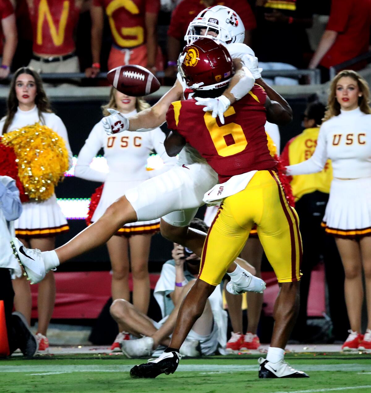 Isaac Taylor-Stuart grapples with Elijah Higgins. USC cheerleaders stand in the background.