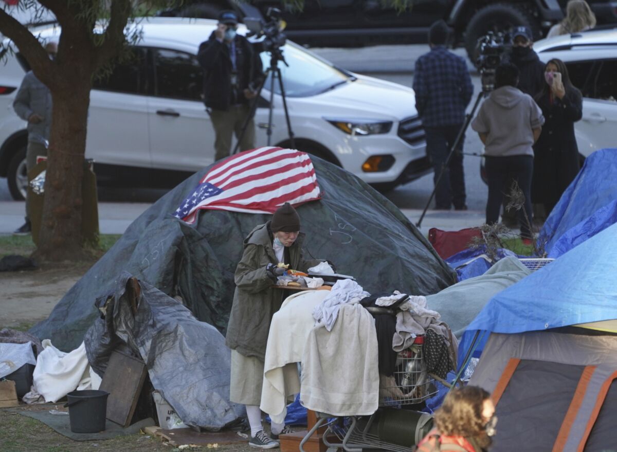 A woman eats at her tent at a homeless encampment in Los Angeles.