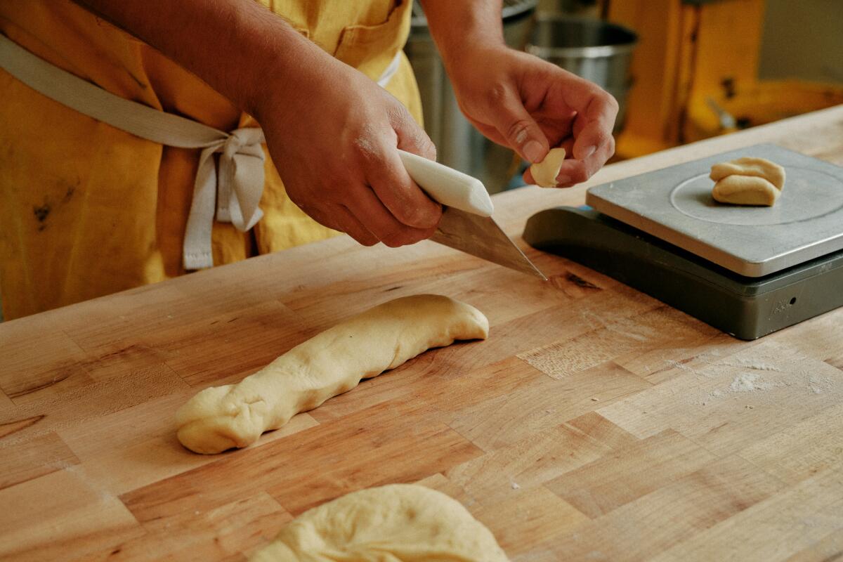 Using a bench scraper to cut a roll of dough into smaller pieces