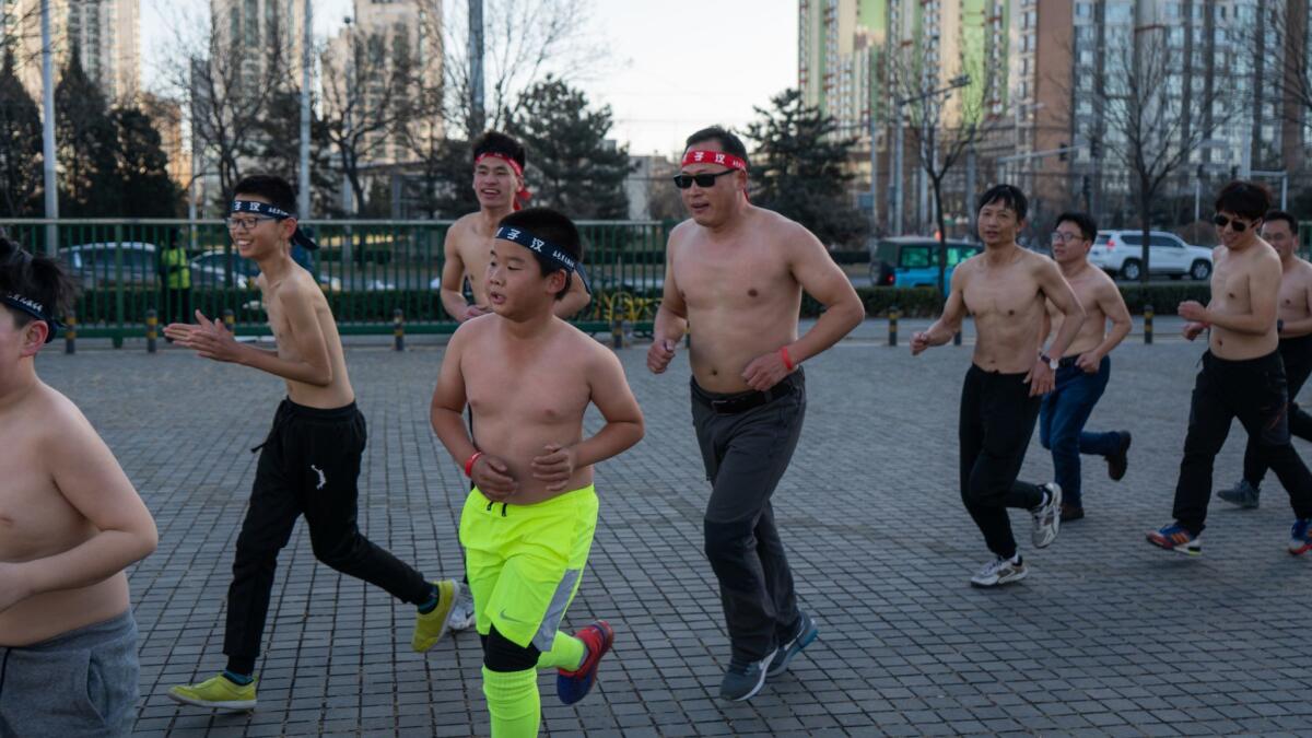 Boys and trainers of the Real Man Training Club run through a Beijing Park in December. Founder Tang Haiyan, center, in sunglasses, also runs with the group.