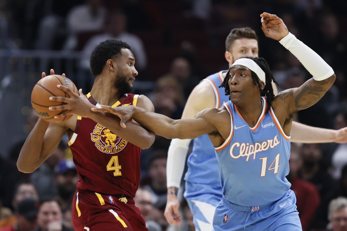 The Clippers' Terance Mann (14) lunges at the ball as Cavaliers' Evan Mobley (4) pull it away