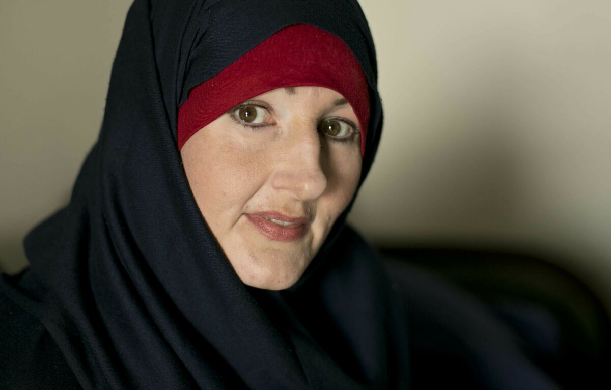 A portrait of a smiling woman in a black head covering 