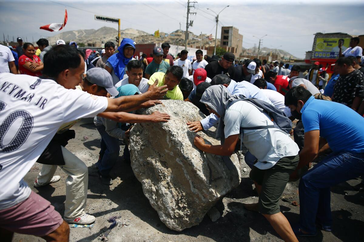 People have their hands on a big rock outdoors.