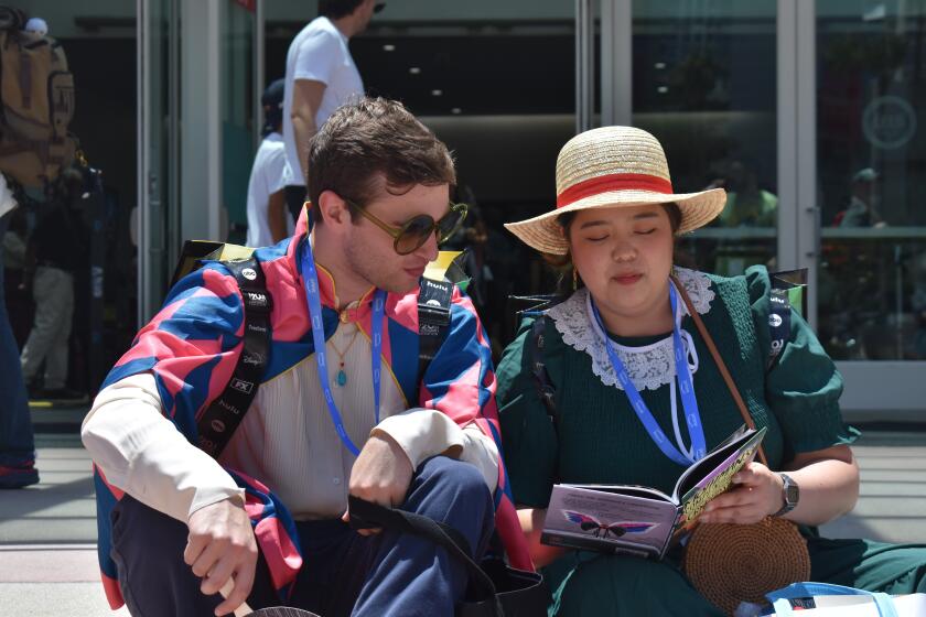 Chris Raffa (left) and Dounia Yang Sawaya read a comic book outside of the San Diego Convention Center.