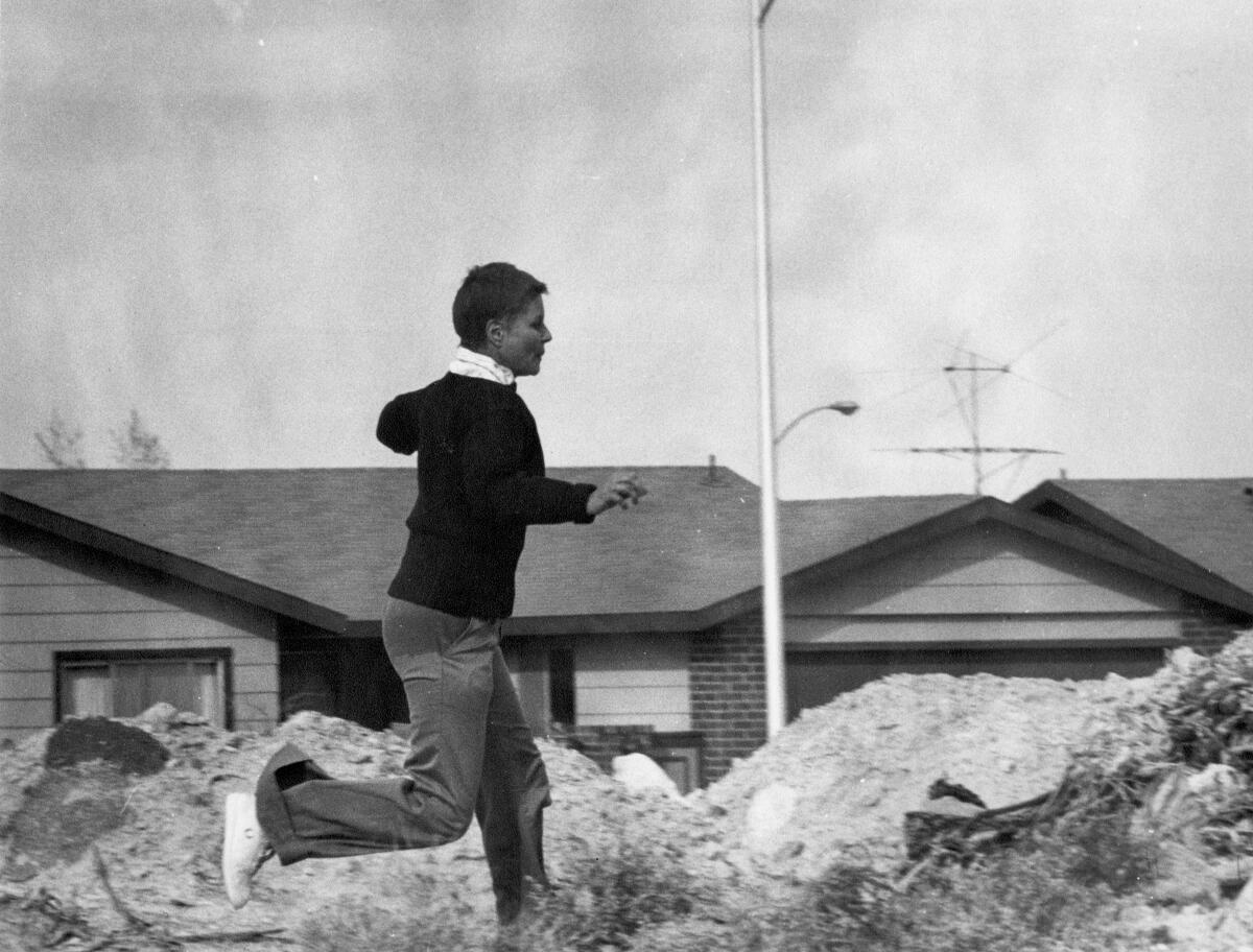 An image of a woman running past suburban, ranch-style homes.