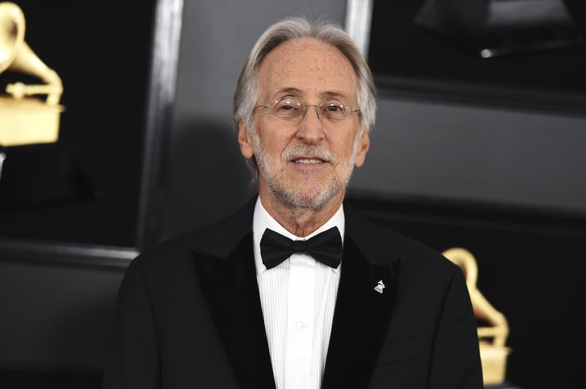 A man with gray hair and beard, wearing a tuxedo