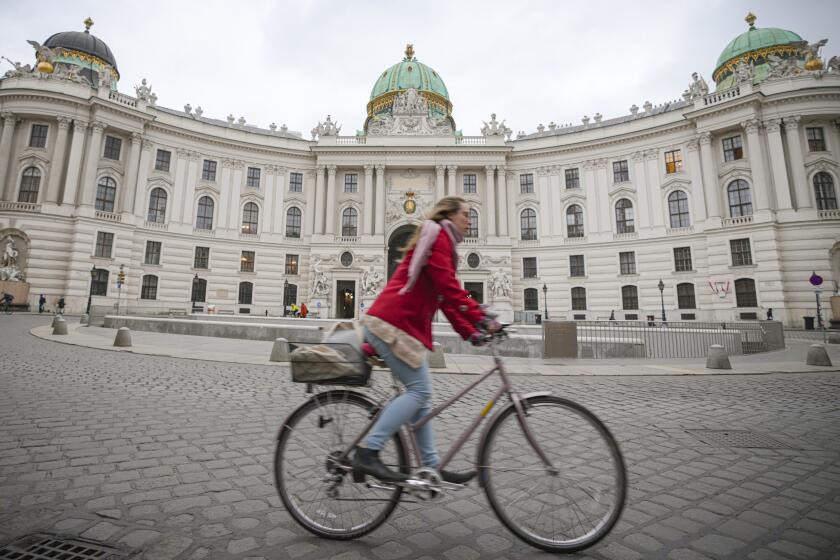 A woman rides a bicycle along an empty street in Vienna, Austria.
