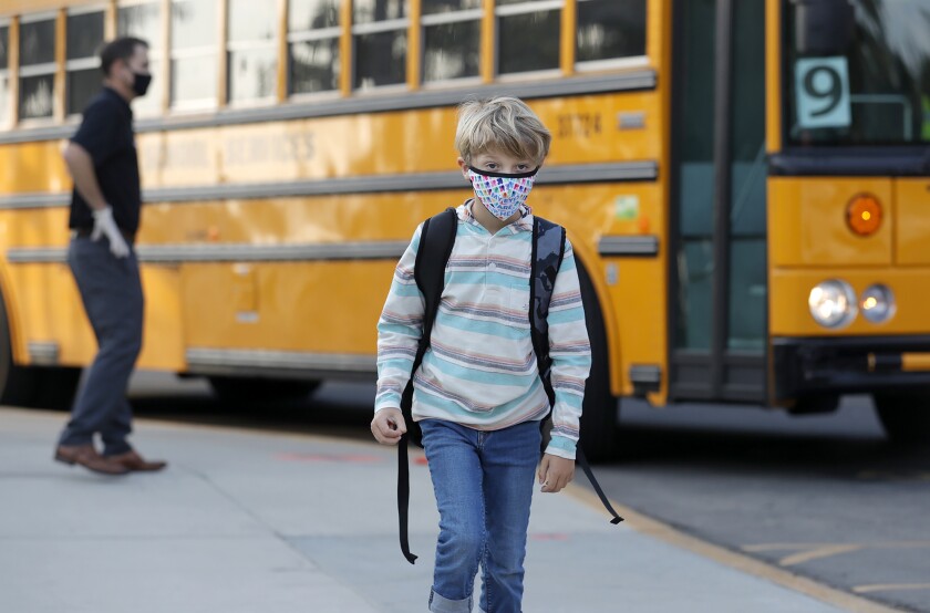 A student arrives on the bus as the children return for an in-person learning at Top of the World Elementary School.
