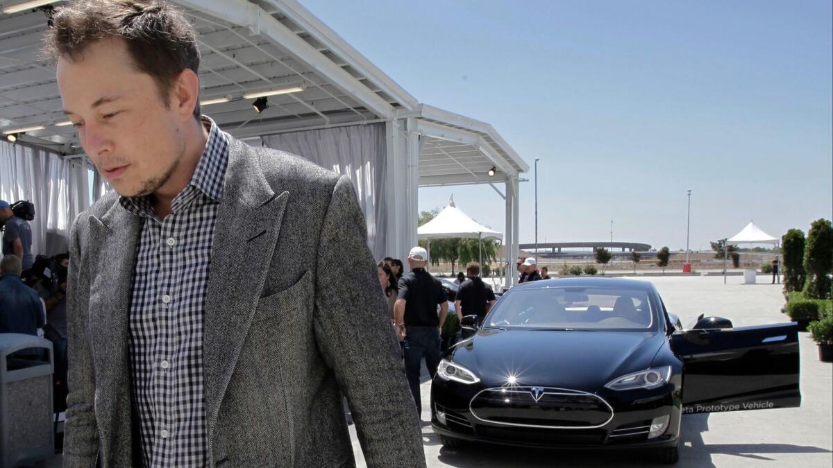 Tesla CEO Elon Musk walks past the Tesla Model S after a news conference at the Tesla factory in Fremont, Calif.