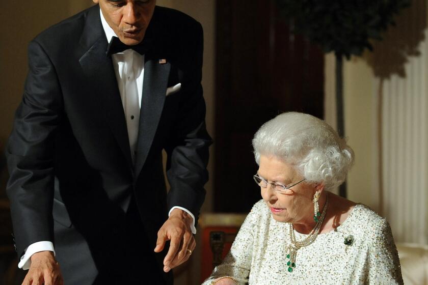 President Obama looks on as Britain's Queen Elizabeth II signs a guest book after a dinner at the Winfield House in London in May 2011.