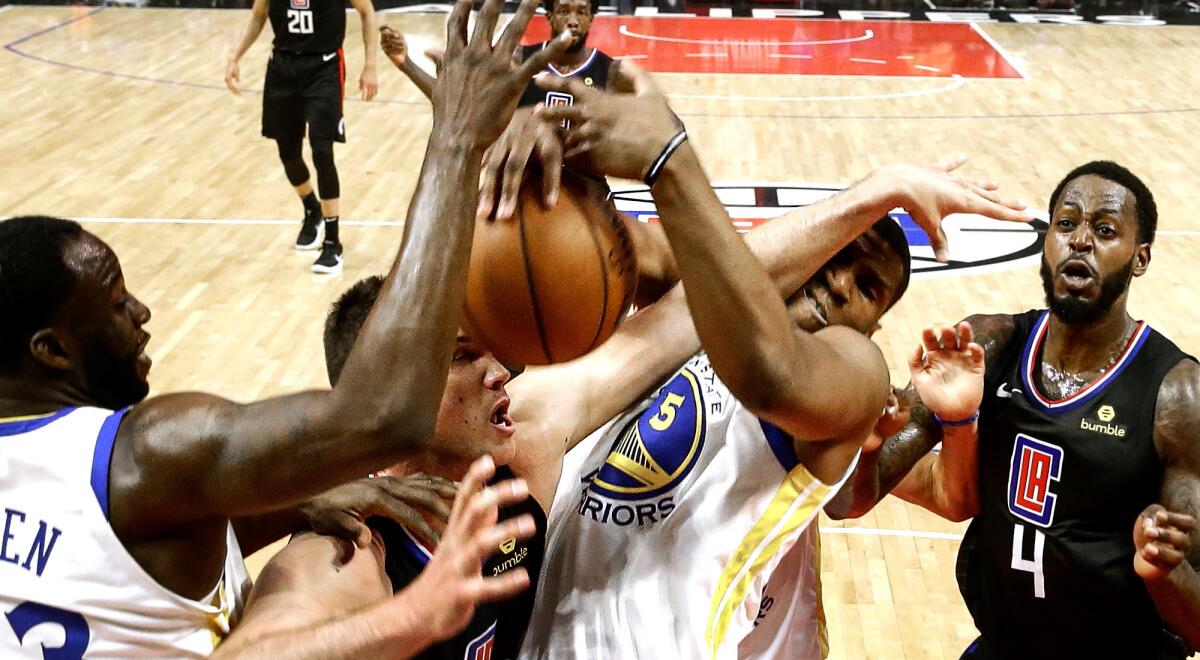 Clippers forward Danilo Gallinari gets caught between Warriors center Kevon Looney (5) and Draymond Green, left, while battling for a rebound during the first half of Game 4.
