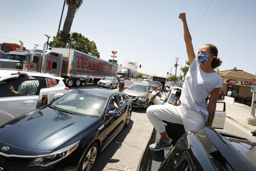 LOS ANGELES, CA - JULY 20: Anya Hayes standing in her vehicle joins local fast food workers, ride-share drivers, Teamsters, and long-term care workers as they blocked Crenshaw Blvd in a demonstration that is part of a nationwide strike for Black lives on Monday. The L.A. vehicle moving rally began at McDonald's Restaurant at 2829 Crenshaw Blvd and was one of 25 sister marches across the United States to call for corporations and the government to "take action to confront triple threat of white supremacy, public health emergency (and) broken economy.'' Los Angeles on Monday, July 20, 2020 in Los Angeles, CA. (Al Seib / Los Angeles Times)