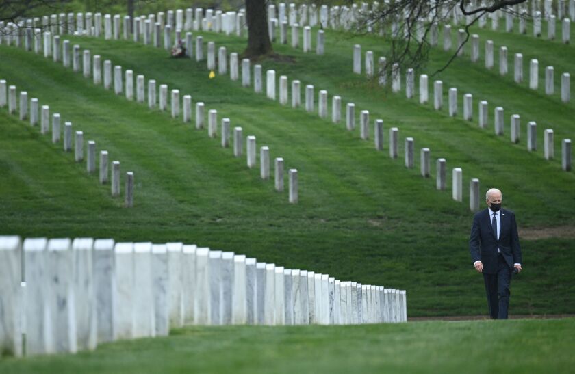 President Biden walks among gravestones at Arlington National Cemetery.
