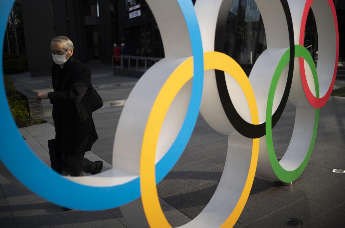 Un hombre pasa al lado de los anillos olímpicos instalados en el exterior del Museo Olímpico de Japón.
