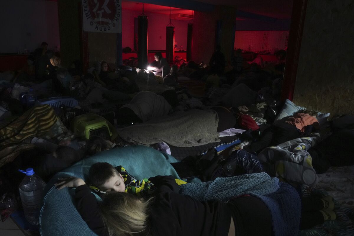 People sleep in an improvised bomb shelter in a sports center