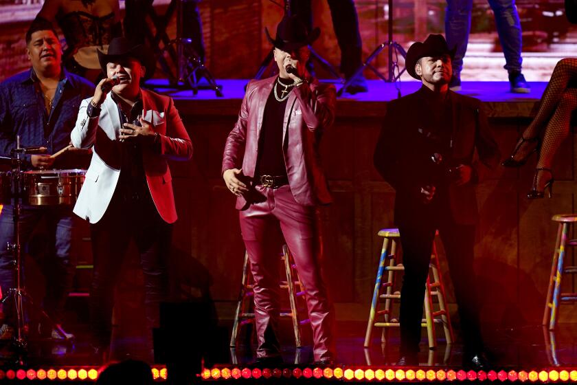 Ab Luna y Eduin Caz del Grupo Firme al lado de Lenin Ramírez en el escenario de Premio Lo Nuestro.