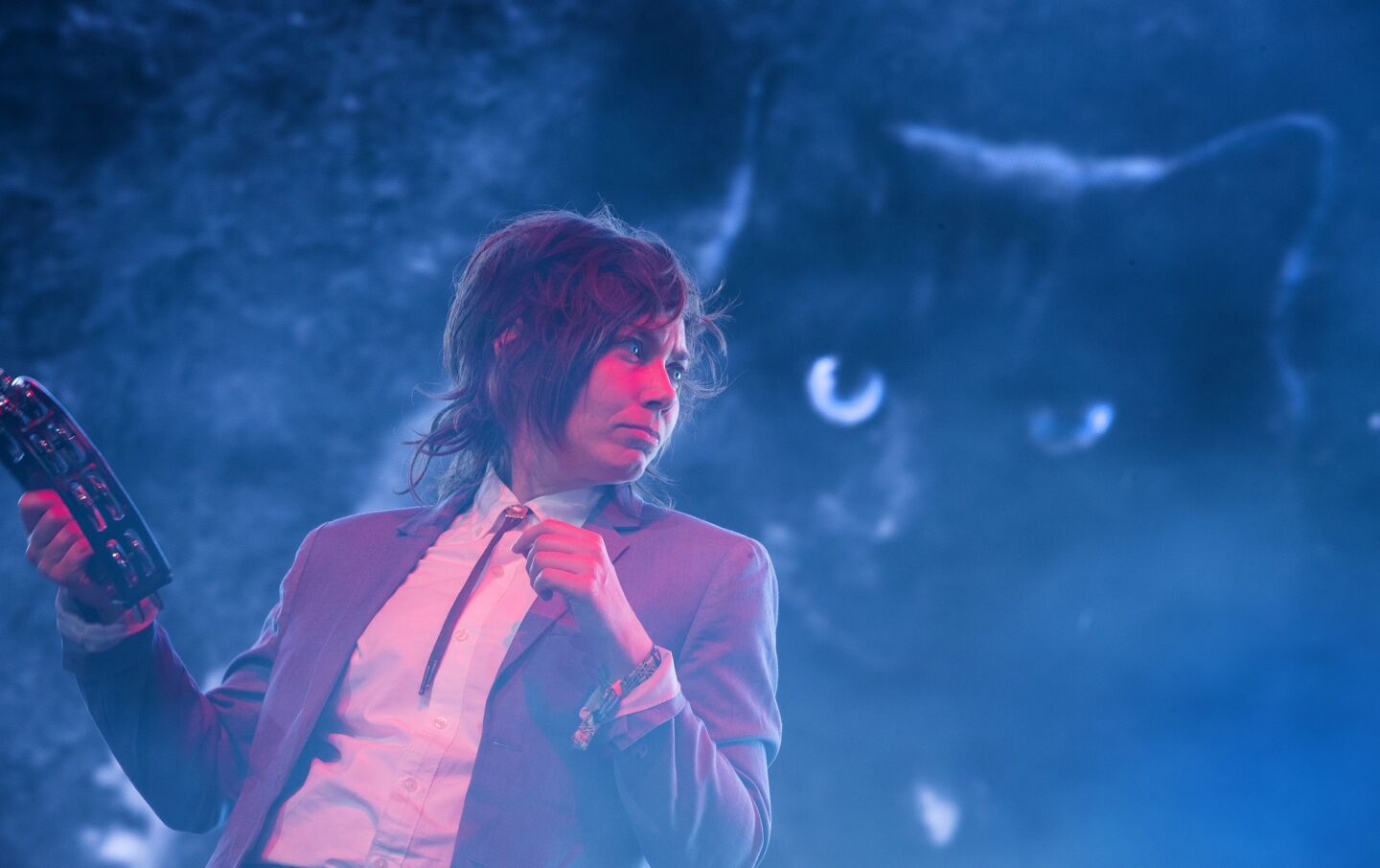 Angel Olsen's keyboardist and backing vocalist (NAME N/A) shakes a tambourine against a backdrop featuring Angel's cat on stage at the Coachella Valley Music and Arts Festival on April 14.