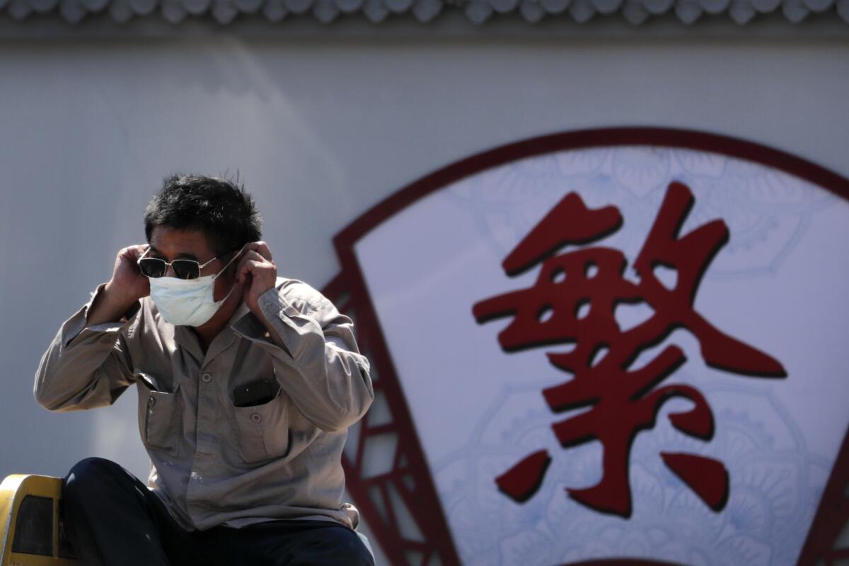 Un hombre se pone su mascarilla facial para protegerse contra el coronavirus en Beijing