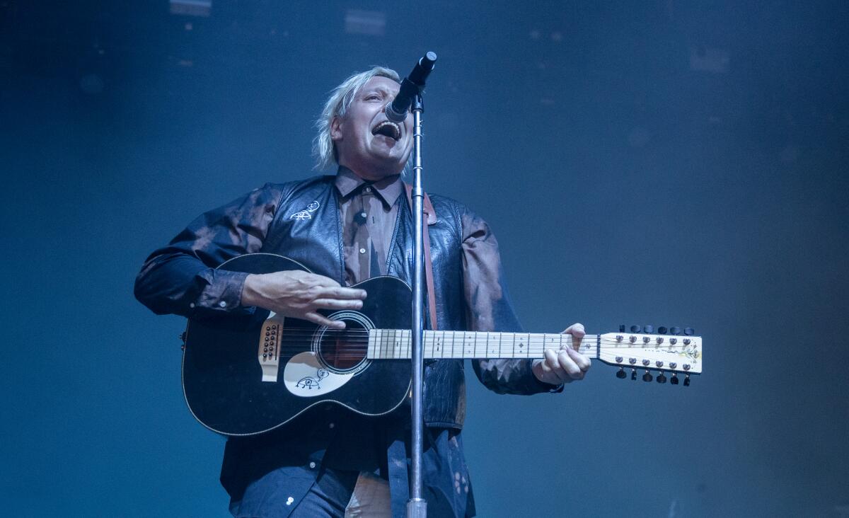 A man sings and plays acoustic guitar onstage