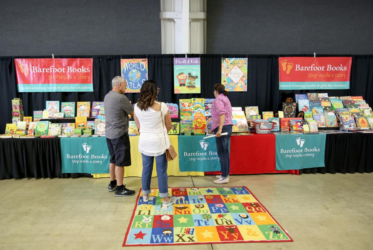 Gina Esguerra, right, of Barefoot Books, shows customers a selection of books at the Home and Holiday Expo in October 2019.