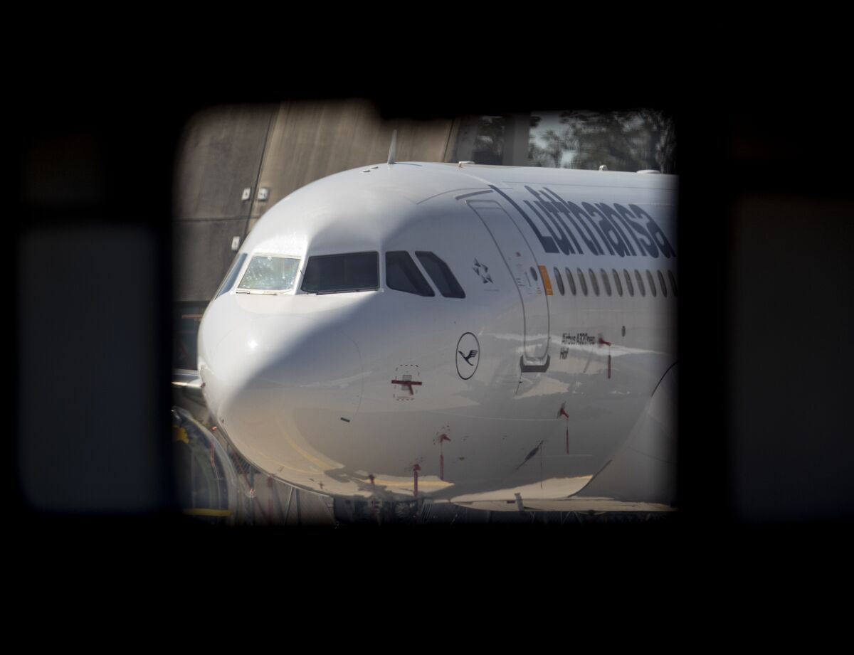 A parked Lufthansa aircraft is seen through a hangar window at the airport in Frankfurt, Germany, Thursday, July 30, 2020. Lufthansa were showing the media how manufacturing has been restarted after the break imposed by the coronavirus outbreak (AP Photo/Michael Probst)