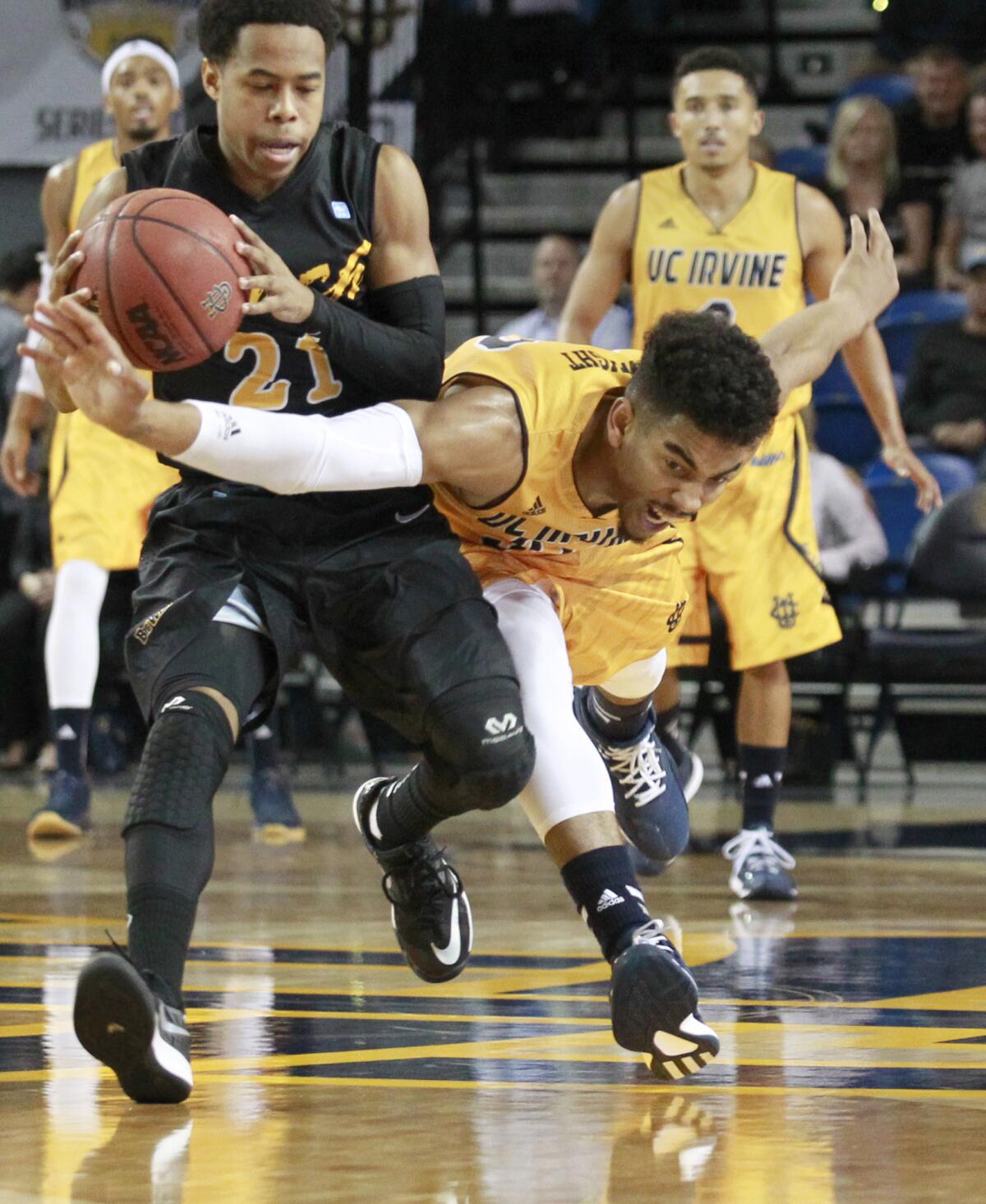 UC Irvine's Aaron Wright, right, battles Long Beach State's Justin Bibbins for a loose ball during the first half in a Big West conference opener game in Irvine on Thursday.