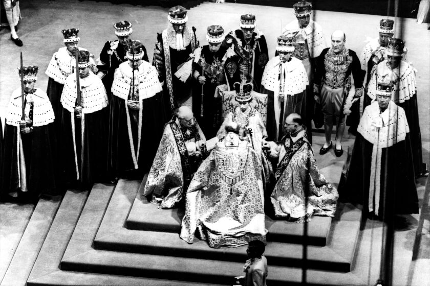 Britain's Queen Elizabeth II, seated on the throne, receives the fealty of the Archbishop of Canterbury, centre with back to camera, the Bishop of Durham, left and the Bishop of Bath and Wells, during her Coronation in Westminster Abbey, June 2, 1953. (AP Photo).