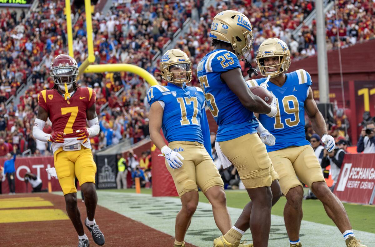 UCLA's TJ Harden (25) celebrates his touchdown with Logan Loya (17) and Kyle Ford (19) against USC on Nov. 18, 2023.