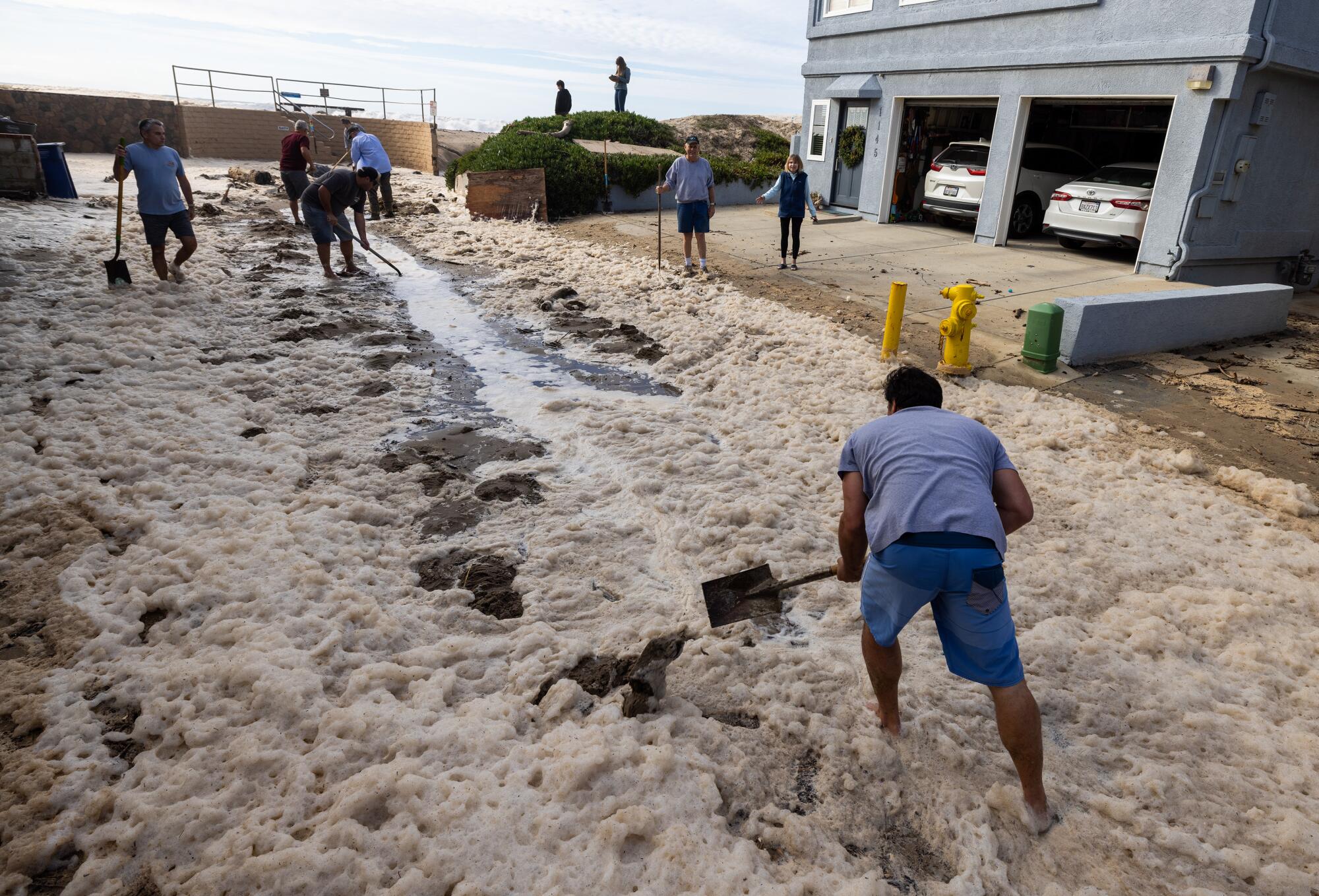 Pierpont neighbors help shovel sand on Bath Lane to help water drain in Ventura.