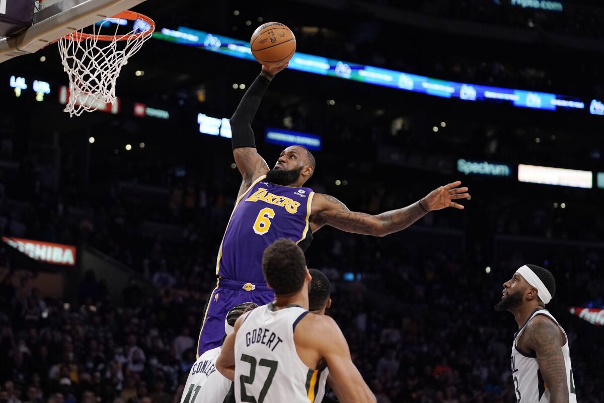 Lakers forward LeBron James dunks as Utah Jazz center Rudy Gobert and forward Royce O'Neale defend.