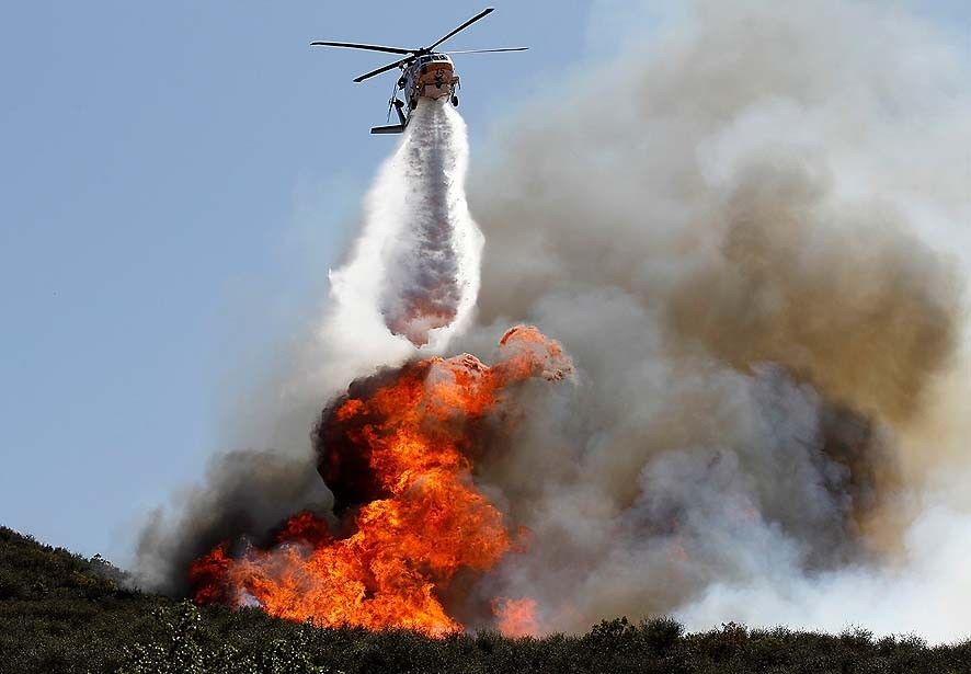 A helicopter makes a water drop on a hot spot in the ridges above Newbury Park.