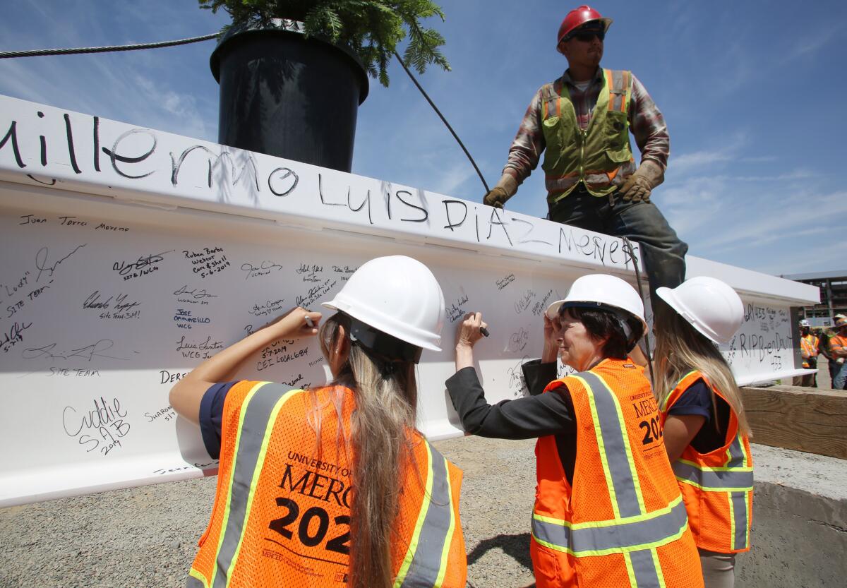 UC Merced Chancellor Dorothy Leland and student leaders sign the final beam of the final building of a project being constructed.