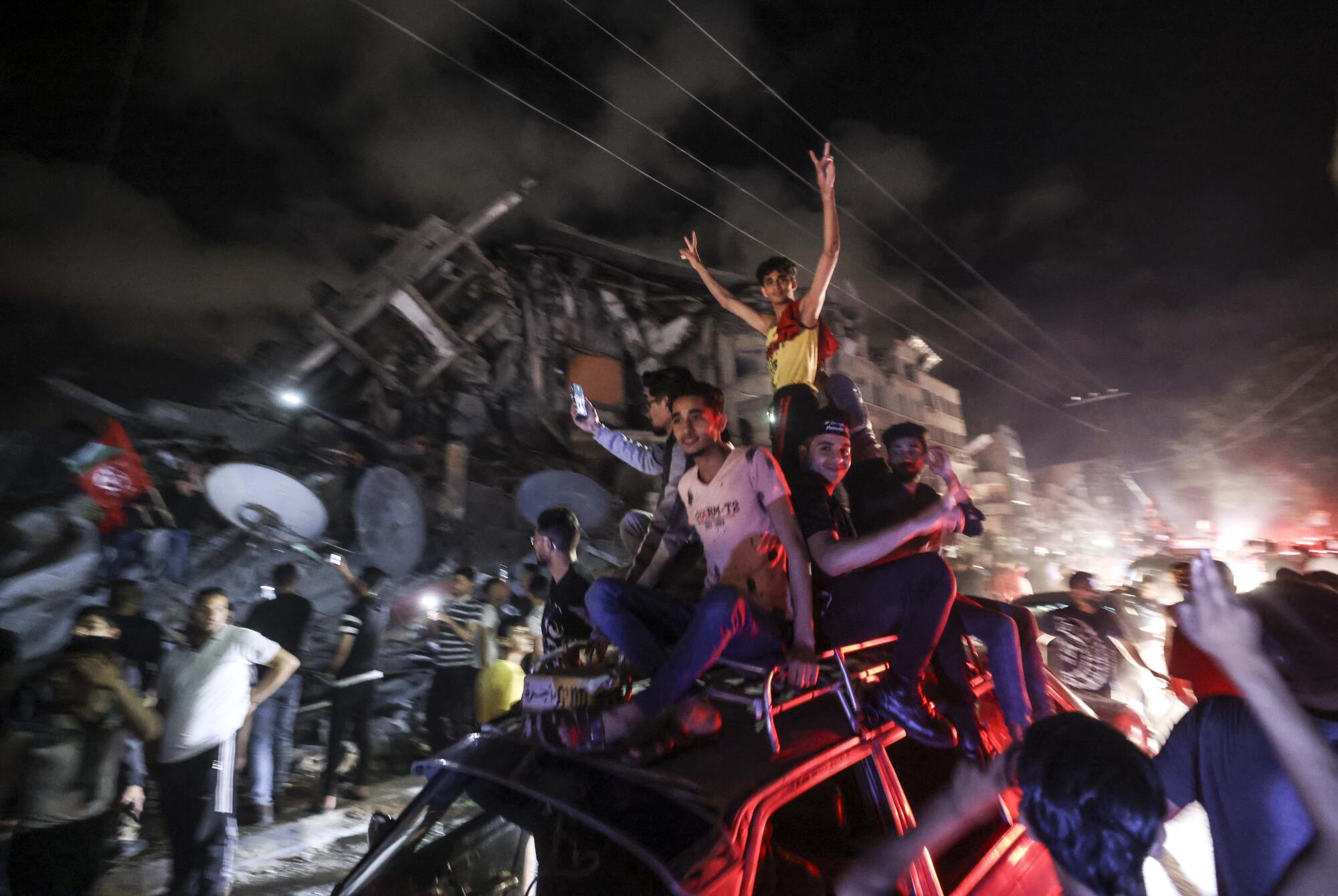 People sit on top of a car as crowds celebrate