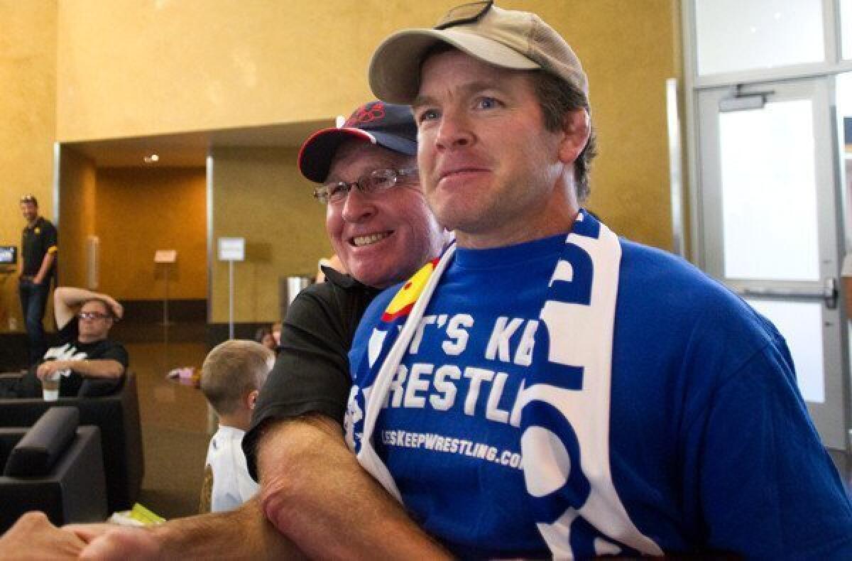 Wrestling legend Dan Gable, left, lifts Iowa associate head coach Terry Brands after the International Olympic Committee voted to to reinstate wrestling for the 2020 Olympics.