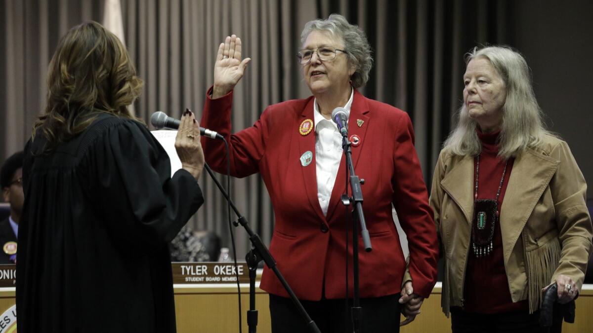 Jackie Goldberg, standing with wife Sharon Stricker, takes the oath of office Tuesday as an L.A. school board member from retired Judge Teresa Sanchez-Gordon. Goldberg had an immediate impact.