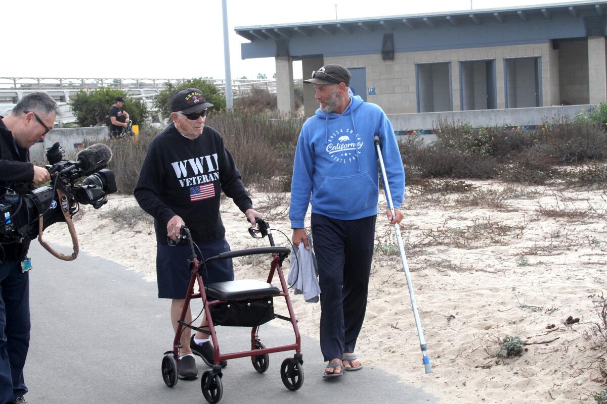 Joe Bush talks with a friend during his morning walk at Bolsa Chica State Beach on Wednesday.